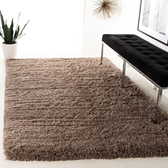 SAFAVIEH Polar Abbot Tapis Shag en Peluche Extrême Uni Couleur taupe Chaud avec une pile Pelucheuse de 3 Pouces d'Épaisseur, Posé sur un Sol Clair à Côté d'Un Banc Capitonné Noir avec des Pattes Chromées et une Plante en Pot, Ajoutant une texture et une dimension Douces à la Déco Maison Moderne.