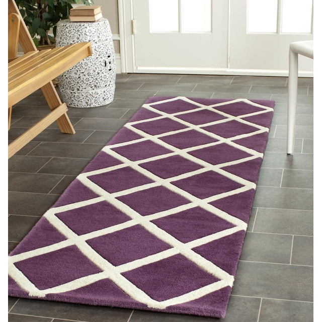 Safavieh Chatham Isaac Geometric Diamonds Area Rug with purple background and white geometric diamond pattern, hand-tufted wool with medium pile for softness, placed on dark grey tile floor near wooden bench and white ceramic stool in a bright room, ideal for contemporary accent decor.