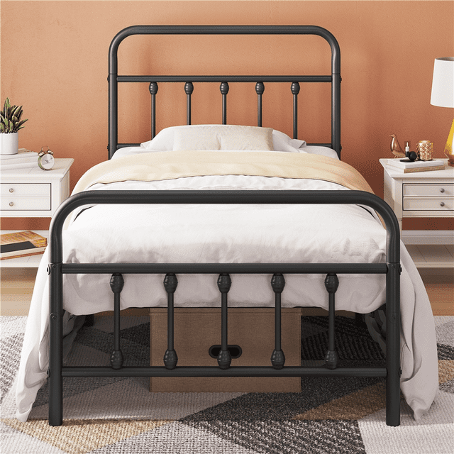 Yaheetech Cadre de Lit Classique en Métal Format Simple avec Tête et Pied de Lit Hauts, Montré en Noir. le Lit Présente des Décorations vintage à Barreaux et des Lignes Courbées Inspirées des Portes d'Entrée Traditionnelles, Créant une Esthétique Ferme et Industrielle. Fabriqué avec un Cadre en Métal Enduit de Poudre pour la Durabilité, Il Comprend 12,6 Pouces d'Espace de Rangement sous le Lit. le Lit Est Exposé dans un Cadre de Chambre Douillet avec des Tables de Nuit Blanches et un Mur aux Tons Chauds.