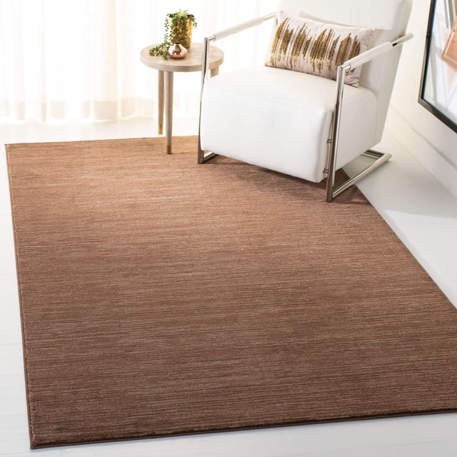 Safavieh Vision Adrasteia Tapis Uni Surteint en Brun Chaud à texture Subtile, Placé dans une Pièce Lumineuse sous un Fauteuil Moderne Blanc avec des Pattes Chromées et un Coussin Décoratif, à Côté d'Une table d'Appoint Ronde avec des Plantes, Convient aux Salons Contemporains Ou aux lofts Urbains Chics et Est Souvent Utilisé comme Tapis d'Accent de Bureau Élégant.