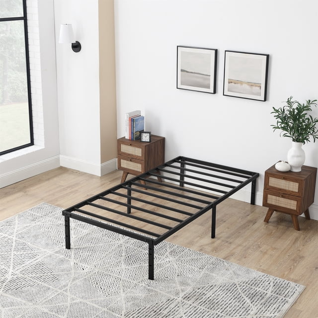 Mainstays Cadre de Lit Plateforme à Lattes en Acier Robuste 14 Pouces pour Lit Simple avec Espace de Rangement sous le Cadre, Aucun Sommier Requis, Noir, Montré dans une Chambre Éclatante avec Plancher de Bois Clair et Murs Blancs. le Cadre en Acier Noir Présente des Lattes Métalliques Horizontales et des Pieds Capuchonnés pour Protéger les Planchers. Il Se Tient à 14 Pouces de Hauteur pour le Rangement sous le Lit et la ventilation du Matelas. Positionné entre Deux Tables de Nuit en Bois avec Façades de Tiroir Tressées, l'Un Tenant des Livres et une Horloge