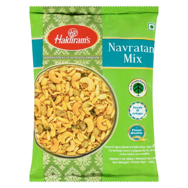 Haldiram Navaratan Chiwda front-facing bowl of Navratan mixture showing golden deep-fried beaten rice flakes, peanuts, cashews and raisins with spice-coated crunchy bits; branded pouch in background listing India as country of origin; often enjoyed as a tea-time Indian snack.