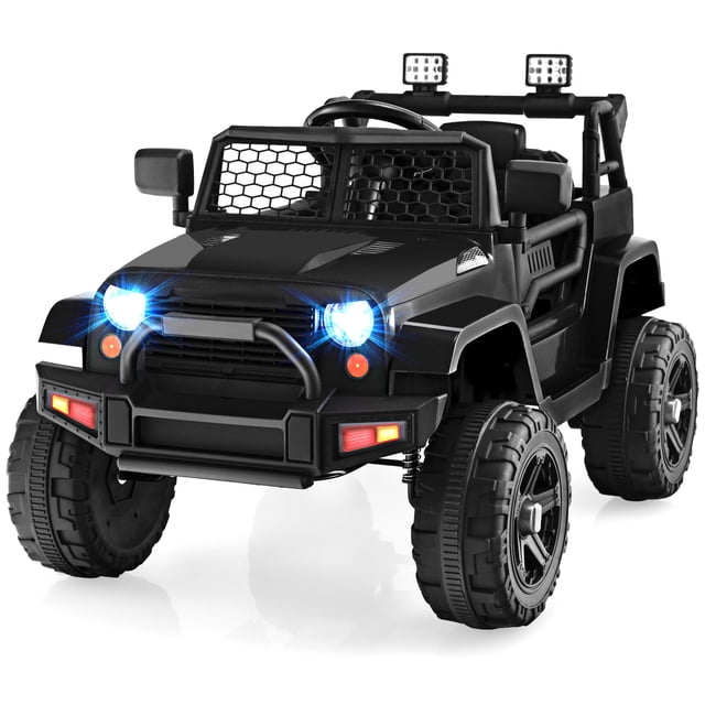 Patiojoy 12V Kids Ride On Car Electric Vehicle Jeep in black, featuring a rugged design with bright LED headlights, a mesh grille, and large treaded wheels. This powered ride-on toy includes a spacious seat with a safety belt, a steering wheel with music and horn buttons, and a slow start function for safety. It offers two operation modes: manual driving for kids and remote control for parents. Suitable for children aged 3-7 years, with a maximum load of 66 lbs and speeds of 1.5-2.8 mph. Ideal for outdoor play and realistic driving experiences.