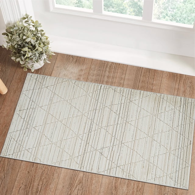 Rug Branch Astra Modern Indoor Area Rug in beige cream with an abstract geometric pattern of intersecting lines and textured stripes, placed on a wood floor near a window with natural light and a potted plant, suitable for living room, bedroom, dining room, and kitchen use.