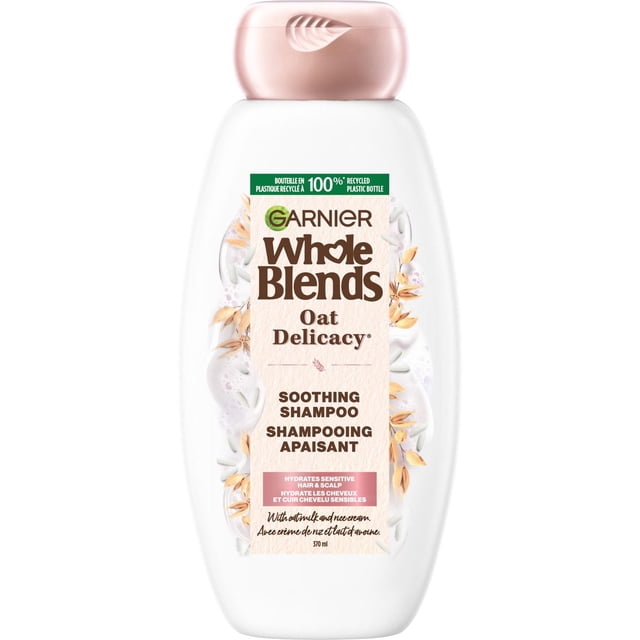 Garnier Whole Blends Oat Delicacy Soothing Shampoo in a 370 ml white plastic bottle with a light pink flip cap, featuring oat and cream graphics on the label, formulated to hydrate and soften sensitive hair and scalp with oat milk and rice cream extracts in a paraben-free formula.