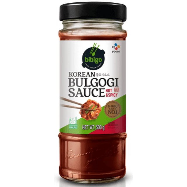 CJ Bibigo Korean Sauce Bulgogi Piquante et Épicée dans un Pot en Verre Transparent avec Couvercle Noir, Présentant une Étiquette Blanche avec accents Verts et Rouges et des Baguettes Tenant de la Viande Marinée, Poids net 500 g, Parfaite pour Marinade, Grillade Ou Sauté de Bœuf, de Porc, de Poulet Ou de tofu avec la Saveur Authentique Korean BBQ et une Chaleur Épicée.