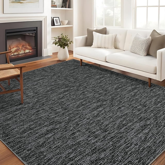 YUSAZENS 5x7 modern washable area rug in black, displayed in a cozy living room setting with a white sofa, wooden chair, and fireplace. The soft, non-slip carpet features a textured pattern, ideal for bedrooms, dining rooms, or living spaces. Made with durable, high-density materials, it resists stains and fading, ensuring longevity and easy maintenance.