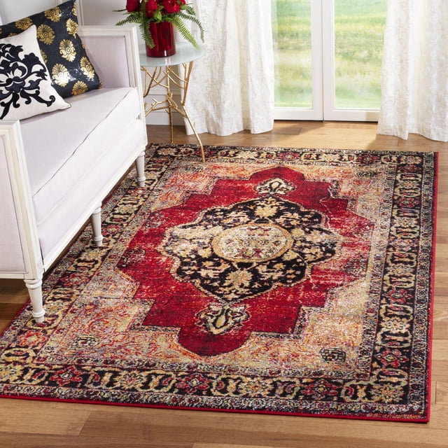 SAFAVIEH Vintage Hamadan Tahnee Traditional Area Rug with Persian-style central medallion in red, black, and gold tones and antique patina, placed on hardwood floor beside a white sofa with decorative pillows and a gold-legged side table with a red vase of flowers, suitable for enhancing vintage home decor.
