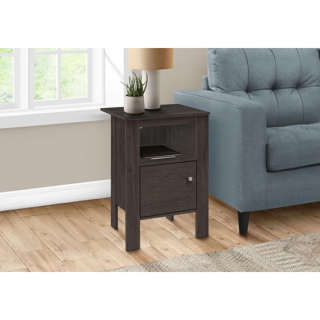 Monarch Specialties Accent Table in dark brown laminate with a rectangular design featuring an open shelf holding a tablet and a closed cabinet with a square silver knob, placed beside a light blue sofa on light wood flooring near a window, topped with a beige lamp and a small potted plant, ideal as a side, end, or nightstand table in living or bedroom areas.