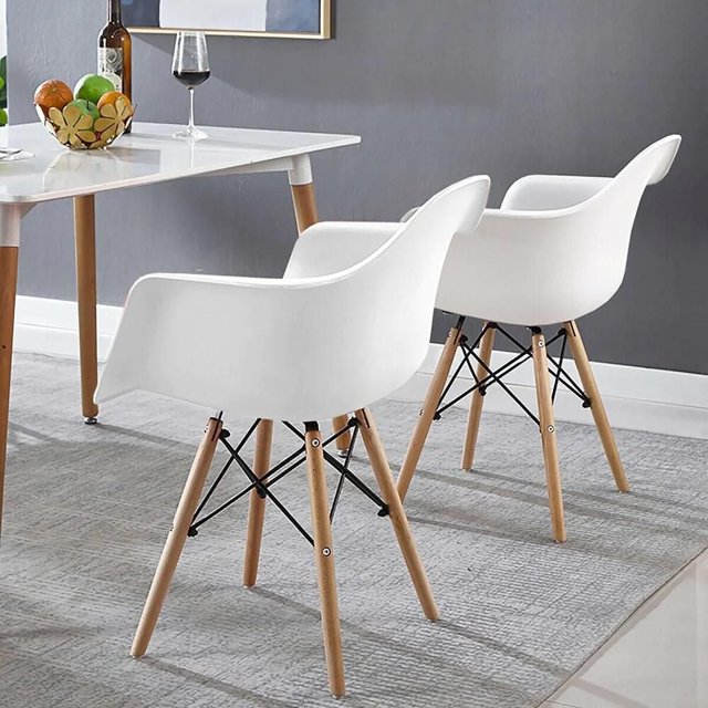Heavenly Collection Plastic White Bucket Chair SET OF 2 with natural Eiffel wood legs and white ABS molded plastic seats, suitable as modern accent chairs for living room seating or dining areas, displayed with a white table and grey wall on a textured rug.