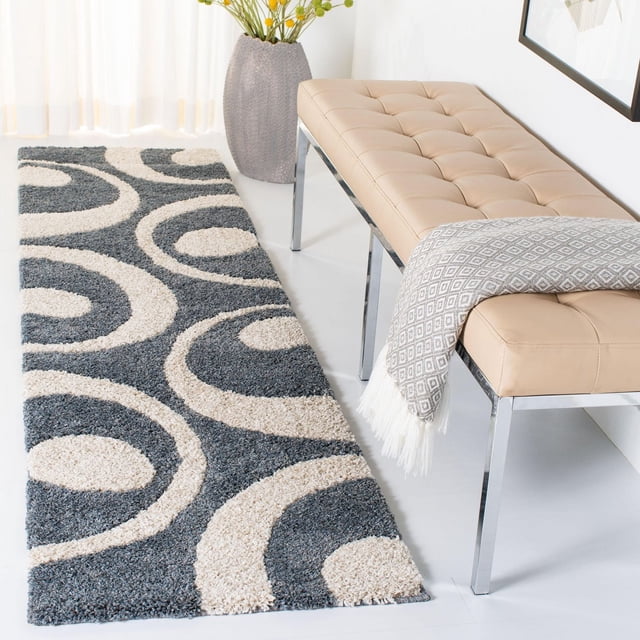 Safavieh Florida Mirabelle Contemporary Shag Area Rug featuring a plush high-low pile with cream circular swirl patterns on a grey background, displayed in a bright room next to a beige tufted bench with chrome legs and a grey diamond-patterned throw, suitable for enhancing modern accent rug areas with soft texture.