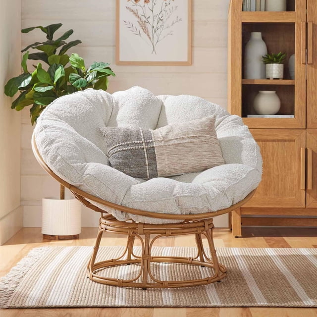 Better Homes & Gardens Emma Fauteuil d'Appoint Papasan avec Cadre Rond en Rotin et Coussin Bouclé Crème Tufté de 4,5 Pouces d'Épaisseur, Incluant un Oreiller Rectangulaire Neutre, Posé sur un Tapis Rayé beige dans un Salon avec Meubles en Bois et une Plante en Pot, Convient pour s'Asseoir de Façon Relaxante.