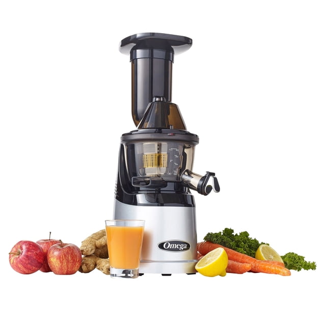 Omega MegaMouth Vertical Low-speed Juicer, a masticating juicer with a silver and black finish, featuring a 3-inch feed chute, rotary cleaning swipe screen, and automatic pulp ejection for easy cleaning. The juicer is displayed alongside fresh produce such as apples, carrots, ginger, kale, and a glass of orange juice, highlighting its ability to process whole fruits and vegetables with minimal heat build-up and oxidation.