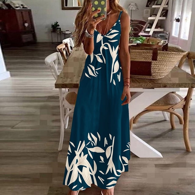 SMihono Robe Maxi Bohème d'Été pour Femmes Grande Taille avec design Sans Manches, Encolure en V et Imprimé en Dentelle. la Robe Est Présentée dans une Couleur Sarcelle avec des Motifs Floraux Blancs, Stylée dans un Décor Décontracté de Plage. Elle a une silhouette Fluide, Longueur au Sol avec Poches Latérales, Idéale pour les occasions d'Été comme les Vacances, les Mariages Ou les Sorties Décontractées.
