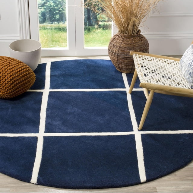 Safavieh Chatham Isaac Tapis à Losanges Géométriques, un Tapis Rond en Laine Tufté à la Main en Bleu Foncé avec des Lignes de Grille Géométriques Blanches, Posé sur un Plancher de Bois Franc Clair avec une Chaise Tissée, un vase en Osier avec des Herbes Séchées, un Cache-Pot Blanc et un pouf Tricoté Brun, Convient à la Déco d'Accent Contemporaine et Ajoute de la Douceur sous les Pieds.