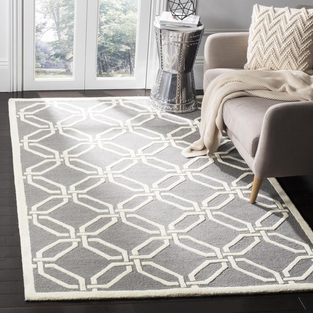 Safavieh Cambridge Kierra Tapis Géométrique pour Aire avec une base en Laine Grise avec un Motif Géométrique Blanc Cassé à Maillons Chaîne, Tufté à la Main avec des piles Peluche Coupées et en Boucle, Placé sur un Plancher de Bois Franc Foncé à Côté d'Un sofa beige avec un Jeté Tricoté Crème et un Coussin, Convient pour Rehausser la Déco Maison Moderne avec texture et style.