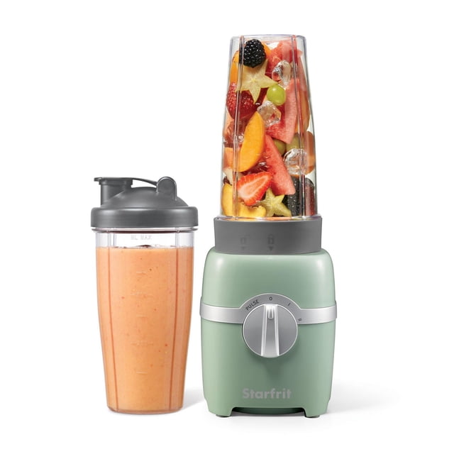 Starfrit 7 pcs 300W Personal Blender in sage green with two 828ml cups, one mounted on the base filled with fresh fruit and ice, and the other with a grey travel lid containing an orange smoothie, featuring a silver control dial with low, high, and pulse speed modes suitable for blending and grinding.