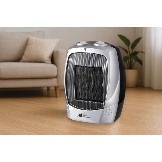 Royal Sovereign Compact Ceramic Heater 1500W in grey and black with front mesh grille and two top control knobs, placed on a wooden floor near a beige sofa and potted plant, featuring LED power indicator and safety functions including overheat and tip-over protection, ideal for quick, quiet room heating.