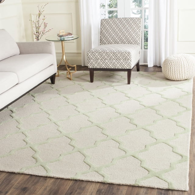 Safavieh Cambridge Tapis Géométrique Liam pour Aire avec Velours Peluche en Laine Tufté à la Main et Motif de Treillis Géométrique Vert Pâle Surélevé sur Crème, Montré dans un Salon avec Planchers de Bois Franc Sombres, sofa beige, Fauteuil d'Appoint à Motifs, table d'Appoint en Verre et pouf Tricoté, Idéal pour Ajouter de la texture et de la Chaleur à la Déco de la Maison.