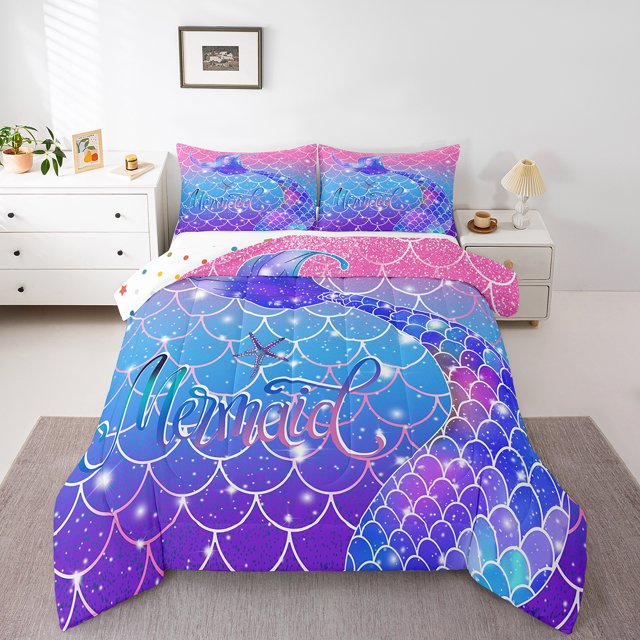 YST Mermaid Fish Scale Bedding Mermaid Tails for Girls Comforter Set Full Size in gradient blue and rainbow colors. The set includes a comforter and two pillowcases, featuring a vibrant mermaid scale design with sparkling details and the word 'Mermaid' prominently displayed. The bedding is styled in a cozy, modern bedroom with white furniture and soft lighting, creating a serene and playful atmosphere.
