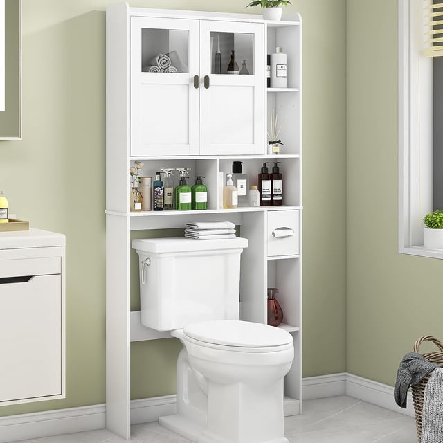 Vabches Over The Toilet Storage Cabinet in white, a freestanding bathroom organizer with glass-front doors, adjustable shelves, and side compartments. Designed to maximize vertical space above a standard toilet, it provides storage for toiletries and essentials in compact bathrooms. Crafted from engineered wood and tempered glass, it includes an anti-tip device for safety and stability.