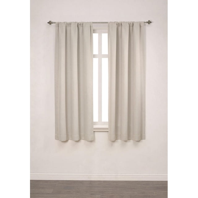 Mainstays Chambray Blackout 63" Window Panel Pair in soft silver heathered texture, hanging on a metal rod over a white-framed window. Each 40-inch wide, 63-inch long panel is made of 100% polyester microfiber with triple foam backing for full blackout, ideal for bedroom light control and privacy.
