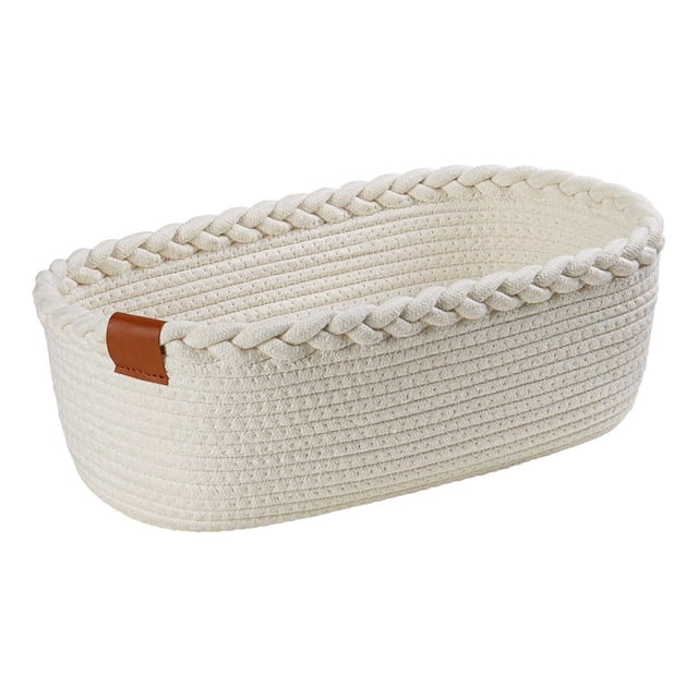 HOMETRENDS Décor Storage basket made from white cotton rope with a braided weave along the top edge and an oval shape, featuring a brown leather accent tab, ideal for stylish home storage and organization, suitable for toiletries, toys, or towels.