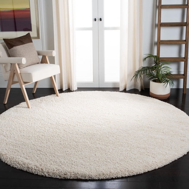 Safavieh Milan Harlow Solid Shag Area Rug, 7-foot round ivory rug with 2-inch thick synthetic shag pile, power-loomed for durability, displayed on dark hardwood floor in a contemporary room with a beige armchair, sheer curtains, and a potted plant, suitable for adding warmth and texture to accent rug areas.