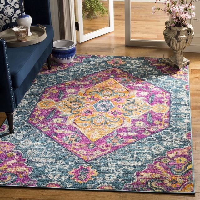 SAFAVIEH Madison Karissa Floral Area Rug displaying a central hexagonal floral medallion in yellow, pink, and blue on a teal and grey background, made from durable power loomed polypropylene, placed on hardwood flooring near a navy blue sofa and decorative ceramic pots, suitable for adding a stylish accent to contemporary and transitional home interiors.