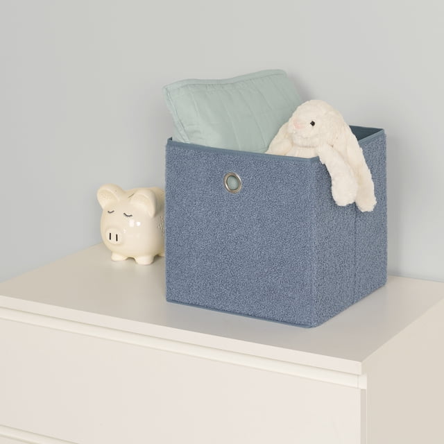 Neatfreak Cube de Rangement Duveteux pour Enfants en Bleu avec un Extérieur Doux Type Teddy, Mesurant 11,1 par 8,7 par 5,7 Pouces, Placé sur une Commode Blanche. Il Contient un Oreiller Matelassé Bleu Pâle et un Lapin en Peluche Blanc, Doté d'Un Oeillet en Métal pour une Manipulation Facile. Convient pour Ranger des Jouets, des Vêtements Ou du Linge.