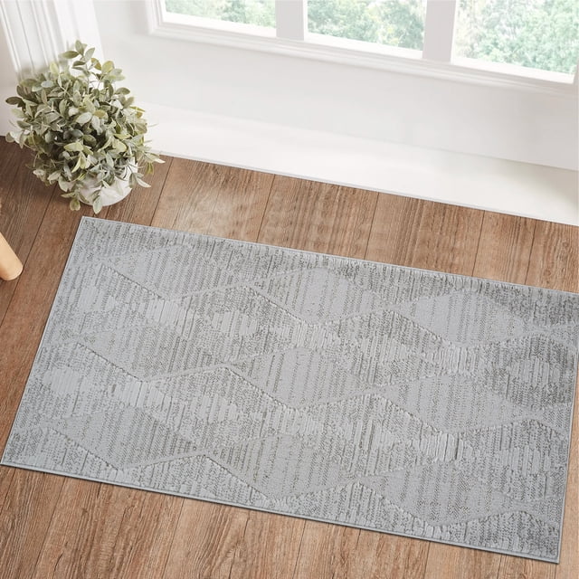 Rug Branch Astra Modern Indoor Area Rug in grey featuring an abstract diamond pattern with textured polyester fibers, placed on a wood floor near a window and a potted plant, designed for living rooms, bedrooms, dining rooms, kitchens, and suitable for high-traffic areas like hallways and entryways.
