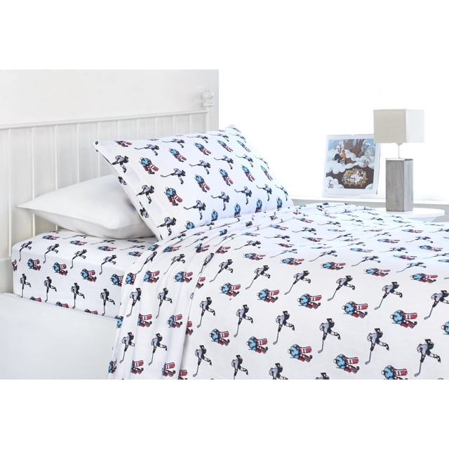Royale Flannel Sheet Sets with a white background featuring a repeated pattern of juvenile hockey players and goalies in blue, black, and red, made from 100% cotton flannel, displayed on a twin bed with a white metal frame and a bedside table with a lamp and framed winter artwork, suitable for brightening a child's bedroom.