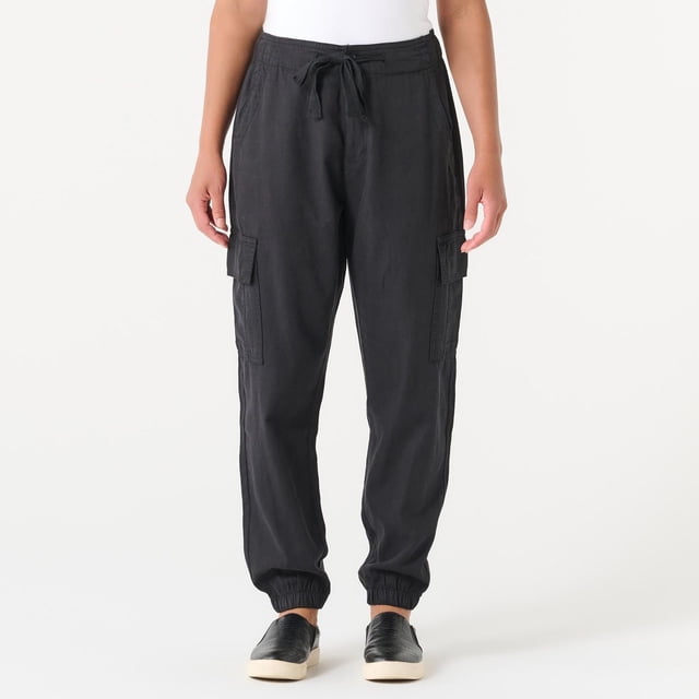 DEVOTED CARGO PANT in grey with a relaxed fit, elastic cuffs, and drawstring waist, featuring flap cargo pockets on both thighs, shown front-facing on a model wearing black slip-on shoes and a white top, ideal for casual and outdoor women's bottoms.