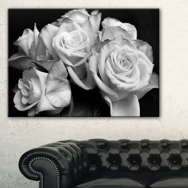 Design Art Bunch of Roses Black And White Floral Canvas Art Print showing a close-up of black and white roses on gallery wrapped cotton canvas with a 1-inch wood subframe, ready to hang, displayed above a black tufted leather sofa in a neutral room, ideal for enhancing home or office wall décor.