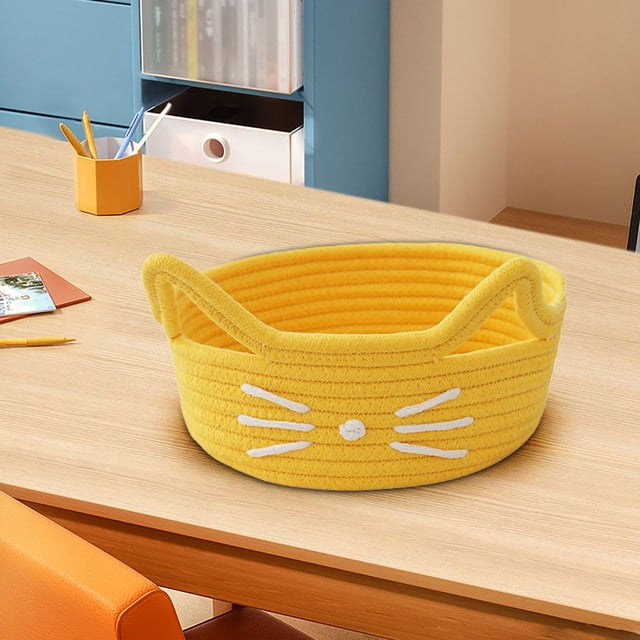 Cats Ear Cottons Thread Organizer Basket in a bright yellow woven cotton rope design with cat ear-shaped edges and white whisker details. The basket is placed on a wooden desk in a modern office setting, surrounded by stationery and storage items. Ideal for organizing cosmetics, snacks, sundries, or desk supplies.
