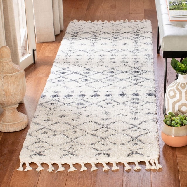 Safavieh Berber Fringe Lesleigh Aztec Shag Tapis de 1,25 Po à Poil Modéré, avec des Motifs Tribaux Aztèques Blancs et Gris Doux et des Franges Modestes, Posé sur Plancher de Bois Franc Près d'Un sofa beige et de la Poterie Décorative, Idéal comme accent boho-chic dans les Espaces de Vie.