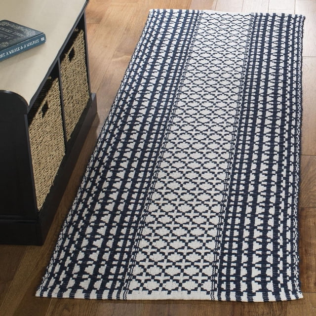 Safavieh Montauk Cara Tapis Géométrique pour Aire, Tapis Coureur en Coton à Tissage Plat avec Motifs Géométriques Inspirés de l'Ikat Bleu Marine et Blanc sur Plancher de Bois Franc, à Côté d'Un Banc de Rangement Noir avec Paniers Tressés, Idéal pour les décor Côtier et Contemporain et Souvent Utilisé comme Coureur de Couloir.