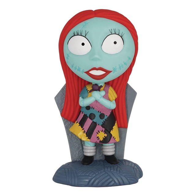 Monogram International Nightmare Before Christmas Sally Tirelire en PVC Mettant en Vedette une Banque Buste Orientée vers l'Avant avec des Cheveux Rouge Vif, Peau Bleue et une Robe patchwork Colorée avec des Motifs Cousus en Jaune, Rose, Noir et Bleu, Debout sur une base Texturée Bleue avec un Fond Gris en Forme de Cercueil, Environ 8,75 Pouces de Hauteur, Idéale pour Ranger de la Monnaie en Vrac et comme Jouet Fantaisie Ou Bocal à Argent.