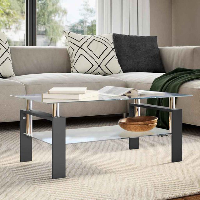 vidaXL Table Basse Noire et Transparente 95x55x40 cm en Verre Trempé Placée dans un Décor de Salon Moderne. la Table Présente un Dessus en Verre Trempé avec une Épaisseur de 6 mm et une Tablette Inférieure avec une Épaisseur de 5 mm, Soutenue par des Pieds Robustes en Mélamine Noire. Sa Conception à 2 Niveaux Offre un Espace de Rangement Supplémentaire, et la Table Est Facile à Nettoyer avec un Chiffon Humide. la Pièce Comprend un sofa Sectionnel beige avec des Coussins à Motifs et Unis, et une Couverture Jetée Verte.