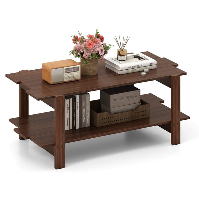 Costway 2-Tier Coffee Table Irregular Center Table with Open Storage Shelf Cocktail Table Walnut. A walnut-finished coffee table with a unique irregular design, ideal for living room furniture. It features a spacious two-tier storage system with a top tier for decorative items like books, flowers, and a radio, and an open lower shelf for storage baskets and books. Made of sturdy engineered wood with thickened legs, it supports up to 270 lbs. The table has ample clearance underneath for robotic vacuum access, combining practicality and elegance for modern living spaces.
