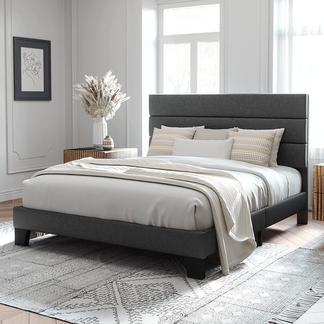 Allewie Cadre de Lit Plateforme Grand Format avec Tête de Lit Rembourrée en Tissu Gris Foncé, Présenté dans une Chambre Contemporaine. le Lit Présente un Cadre durable en Métal et Bois avec une Capacité de Poids de 800 Livres, une Tête de Lit Rembourrée avec Panneaux Horizontaux et des Bouchons de Pied en Plastique pour Prévenir les Égratignures du Plancher. Conçu pour un Assemblage Rapide, Comprend des Outils et des instructions. Conçu avec une Literie Neutre et des Coussins Décoratifs, le Lit Repose sur un Tapis à Motif, Idéal pour les Installations Modernes de Meubles de Chambre.