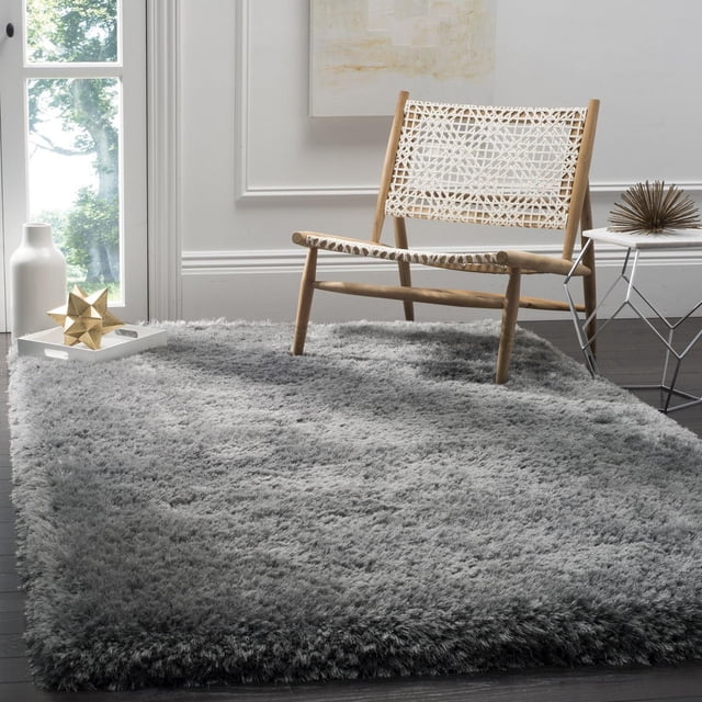 Safavieh Luxe Paxton Solid Plush Shag Area Rug, grey, 2'3" x 8' runner made of hand-tufted synthetic yarns for plush texture and vibrant colour, shown on dark hardwood floor with a woven wooden chair and modern side table in a bright room.