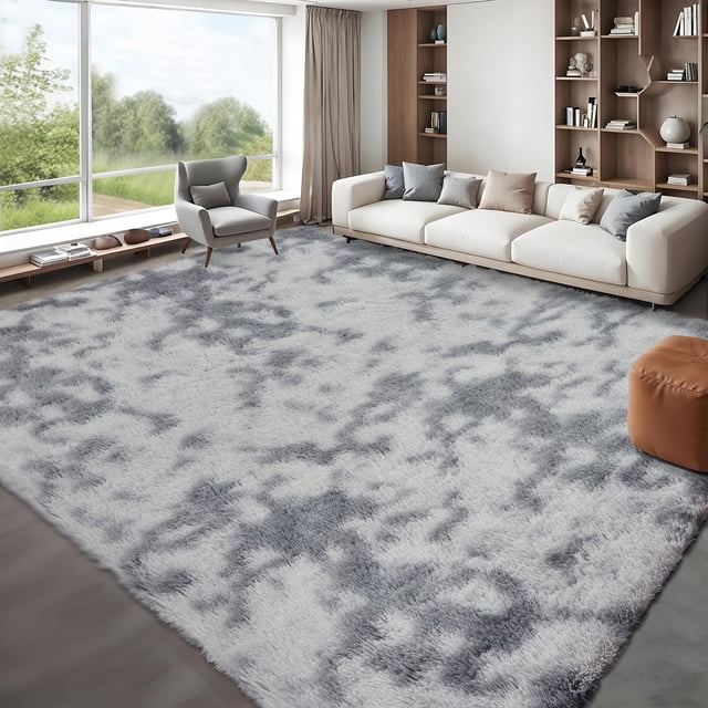 HOMERRY Abstract Plush Shag Area Rug 8'x10' in light gray displayed in a modern living room setting. The rug features a high-density faux fur pile measuring 1.57 inches, offering ultra-plush comfort and a smooth texture. Its anti-slip bottom with thousands of grip dots ensures stability on hard floors. The light gray color and abstract pattern complement the neutral-toned furniture, including a white sectional sofa, a grey armchair, and a brown ottoman. Large windows provide natural light, enhancing the cozy and inviting atmosphere.
