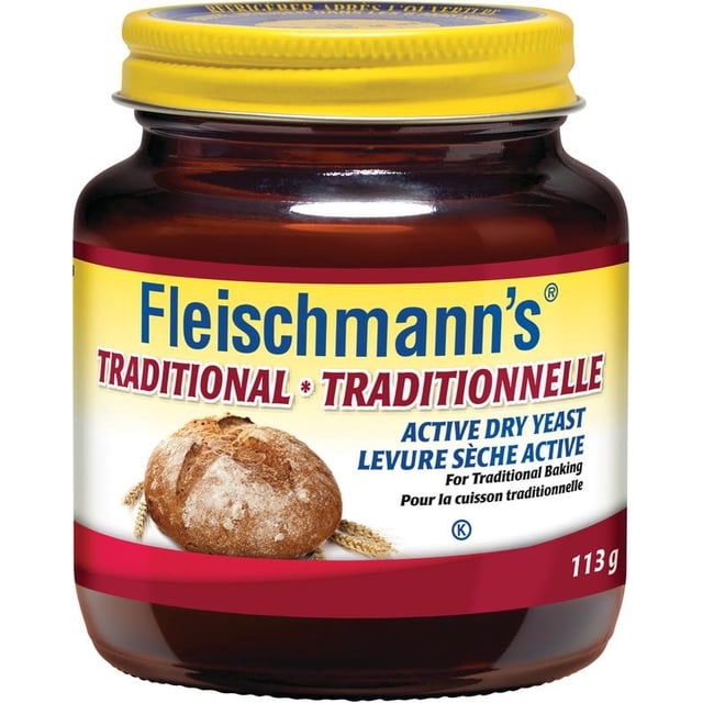 Fleischmann's Traditional Yeast jar with yellow lid and brown glass container, labeled active dry yeast for traditional baking, featuring a round bread loaf and wheat stalks, weighing 113 grams, suitable for bread and dough preparation.