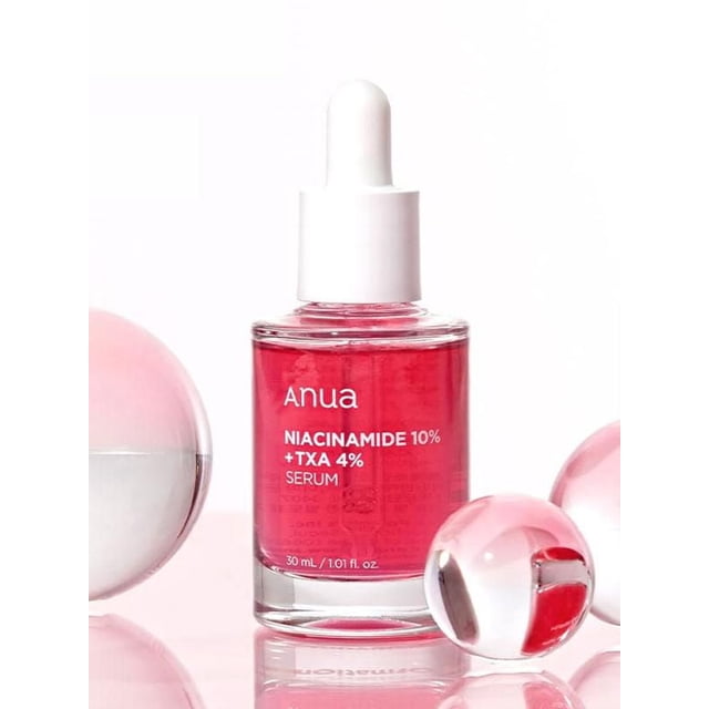 Anua Niacinamide 10 % + TXA 4 % Serum 30 ml dans une Bouteille en Verre Transparent avec Bouchon Compte-Gouttes Blanc, Contenant du Liquide Rose Vif, Présenté avec des Sphères en Verre Réfléchissantes Roses et Transparentes sur Fond Blanc, Formulé pour Réduire l'Hyperpigmentation et Soutenir la Barrière d'Hydratation de la Peau.