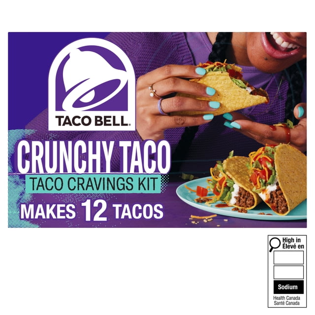 Taco Bell Crunchy Taco Cravings Kit Boîte de 260 g avec Fond Violet et logo Taco Bell, Indiquant Que Ça Fait 12 tacos Croquants. une Personne avec Vernis à Ongles turquoise Tient un tacos Croquant Rempli de Bœuf Haché Assaisonné, de Laitue, de Fromage Râpé et de Tomates en dés, avec Deux tacos sur une Assiette Bleue à Proximité.