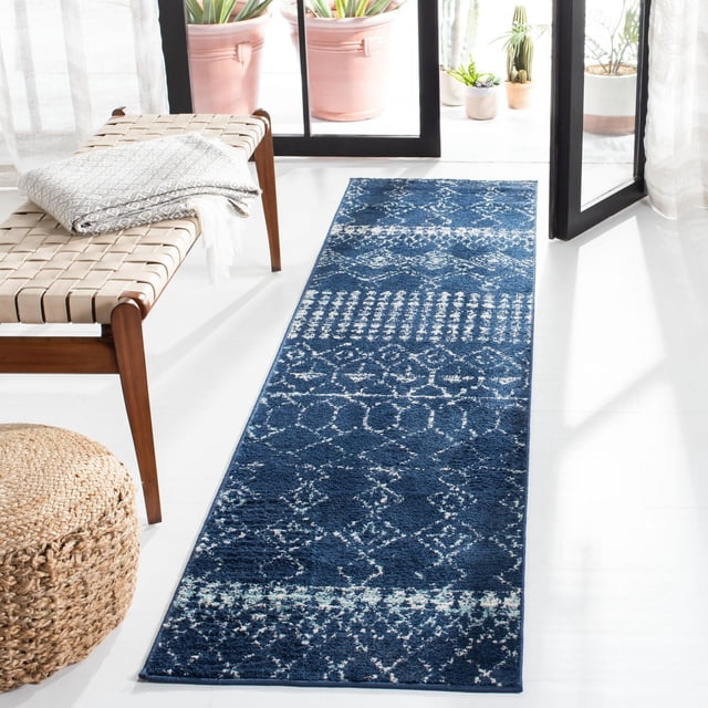 Safavieh Tapis Géométrique Marocain Tulum Coriandre Bleu Foncé avec Motifs Géométriques Blancs, Noué à la Main en Laine fine, Posé sur un Plancher Blanc Près d'Un Banc en Cuir Tressé avec un Jeté Gris Plié et un pouf en fibre Naturelle Tressée, à Côté de Portes en Verre s'Ouvrant sur un patio avec pots en Terre Cuite et Succulentes, Idéal pour Ajouter Chaleur et style à la Déco Contemporaine de la Maison.