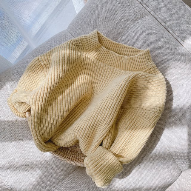 Kmbangi Children's Sweater+Infant's Solid Pullover Striped Pit Bar Long Sleeve Top in a soft yellow color, crafted from breathable knitting fabric. This baby boy sweater features a crew neck and full-length sleeves, displayed on a beige cushioned surface with natural lighting. Available in sizes for ages 0-6 months to 5-6 years, it provides a cozy fit for daily wear, parties, or photography.