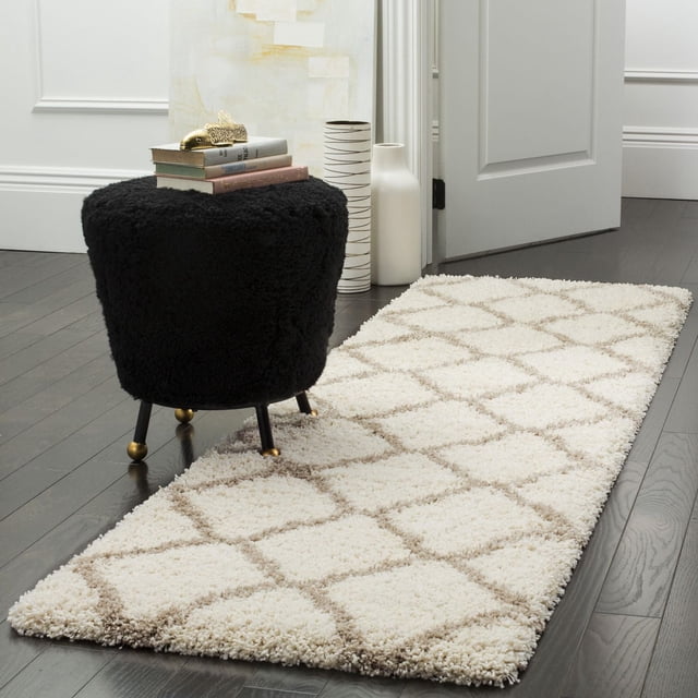 Safavieh Hudson Tapis Coureur à Motif Shag Géométrique Ligne a avec pile en Fil Synthétique Crème Peluche et Motif Géométrique de Carreaux Marocains Brun Pâle sur Plancher de Bois Franc Foncé à Côté d'Un ottoman Texturé Noir avec Pieds Dorés et Livres Empilés, dans une Pièce Minimaliste à Parois Blanches avec vases Décoratifs, Convient pour Ajouter Chaleur et style aux Couloirs Ou Entrées Étroits.
