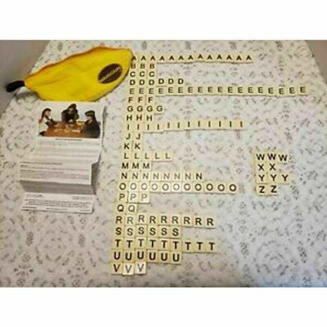 1 set Word Play Family Fun Game Bananagrams Crossword Kids Boy Toy featuring a yellow banana-shaped pouch with a zip fastener, plastic letter tiles arranged in a grid, and instruction cards. The game is designed for fast-paced, educational wordplay and is suitable for family use or travel. Each tile measures approximately 2 cm x 2 cm, and the pouch dimensions are 6 cm x 22 cm x 6 cm.